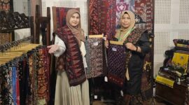 SINERGI PELESTARIAN BUDAYA: Ketua Persit KCK Cabang XXIII Kodim 0415/Jambi, Ny. Chichi Putra Negara (kiri), bersama Ny. Ruslaini Fadli (kanan) menunjukkan kain Batik Jambi motif unggulan di Booth 65 pameran 