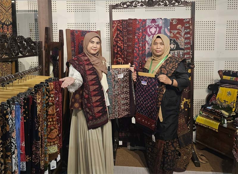 SINERGI PELESTARIAN BUDAYA: Ketua Persit KCK Cabang XXIII Kodim 0415/Jambi, Ny. Chichi Putra Negara (kiri), bersama Ny. Ruslaini Fadli (kanan) menunjukkan kain Batik Jambi motif unggulan di Booth 65 pameran 