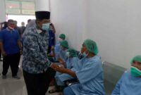 Bupati Tanjung Jabung Barat H. Anwar Sadat menyalami Warga yang akan menjalani Operasi Mata, Minggu (21/8/22). FOTO : Ist