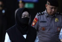 Bupati Sukoharjo Etik Suryani (tengah) berjalan dengan kawalan ketat petugas kepolisian usai menjalani pemeriksaan awal di Mapolresta Surakarta, Jawa Tengah, Jumat (10/7/2026). (Foto: Dok. Istimewa/CNNIndonesia.com)