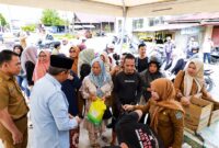 Bupati Anwar Sadat (berpeci, baju biru), meninjau langsung pendistribusian komoditas pangan murah kepada masyarakat di Toko Berkah Jaya, Kuala Tungkal, Senin (25/5). Operasi pasar murah ini digelar sebagai langkah taktis pemerintah daerah bersama Perum Bulog untuk menjaga stabilitas harga dan mengamankan daya beli warga menjelang Hari Raya Idul Adha 1447 Hijriah. (FOTO : Dok. Prokopim TJB)