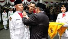 Bupati H. Anwar Sadat, menyematkan Lencana Merah Putih Garuda secara simbolis kepada pemimpin upacara dalam prosesi Pengukuhan 45 Anggota Pasukan Pengibar Bendera Pusaka (Paskibraka) Kabupaten Tanjung Jabung Barat Tahun 2026 di Halaman Rumah Dinas Jabatan Bupati, Sabtu (15/8/2026). (FOTO : Dok. Prokopim)