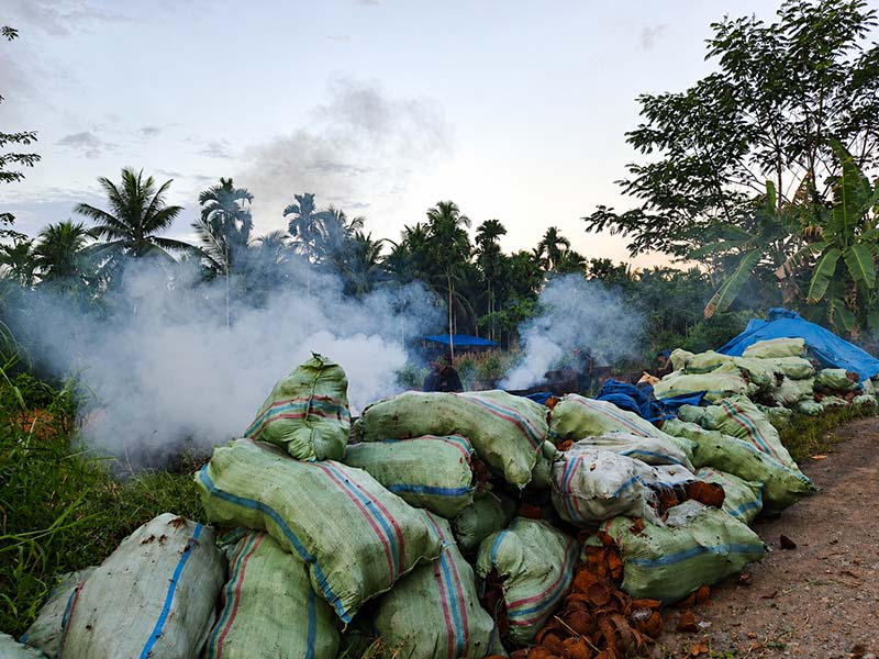 Kepulan asap tebal membubung dari lokasi pembakaran arang tempurung kelapa yang dikeluhkan mengganggu kenyamanan dan kesehatan warga Desa Kemuning. Camat Bram Itam menegaskan seluruh pengrajin wajib mematuhi SE Bupati terkait pembatasan jam operasional. (Foto: Dok. Istimewa)