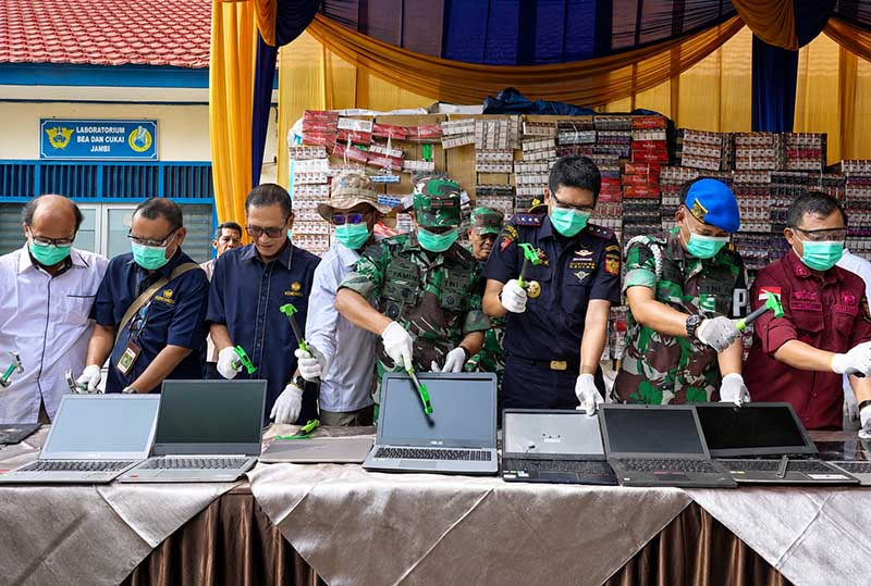 Kepala Kantor Bea Cukai Jambi, Dafit Kasianto (kanan baju hitam), dan sejumlah pejabat instansi terkait secara simbolis menghancurkan laptop bekas ilegal menggunakan palu saat pemusnahan Barang yang Menjadi Milik Negara (BMMN) di halaman Kantor Bea Cukai Jambi, Rabu (24/6/2026). (Foto: Penrem 042/Gapu)