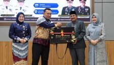 Bupati Tanjab Barat H. Anwar Sadat menyerahkan plakat penghargaan dan cindera mata kepada AKBP Maulia Kuswicaksono sebagai bentuk apresiasi atas dedikasinya selama menjabat sebagai Kapolres Tanjung Jabung Barat, Jumat (11/09/2026). (FOTO : Dok. PROKOPIM)