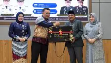 Bupati Tanjab Barat H. Anwar Sadat menyerahkan plakat penghargaan dan cindera mata kepada AKBP Maulia Kuswicaksono sebagai bentuk apresiasi atas dedikasinya selama menjabat sebagai Kapolres Tanjung Jabung Barat, Jumat (11/09/2026). (FOTO : Dok. PROKOPIM)