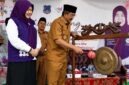 Bupati  H. Anwar Sadat, didampingi Ketua Tim Pembina Posyandu Kabupaten Hj. Fadhilah Sadat, S.H., melakukan pemukulan gong sebagai tanda peluncuran Posyandu 6 Standar Pelayanan Minimal (SPM) Percontohan Cempaka II di Desa Pematang Lumut, Kecamatan Betara, Senin (6/7). (Foto: Diskominfo Tanjab Barat)