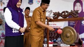 Bupati  H. Anwar Sadat, didampingi Ketua Tim Pembina Posyandu Kabupaten Hj. Fadhilah Sadat, S.H., melakukan pemukulan gong sebagai tanda peluncuran Posyandu 6 Standar Pelayanan Minimal (SPM) Percontohan Cempaka II di Desa Pematang Lumut, Kecamatan Betara, Senin (6/7). (Foto: Diskominfo Tanjab Barat)