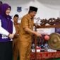 Bupati  H. Anwar Sadat, didampingi Ketua Tim Pembina Posyandu Kabupaten Hj. Fadhilah Sadat, S.H., melakukan pemukulan gong sebagai tanda peluncuran Posyandu 6 Standar Pelayanan Minimal (SPM) Percontohan Cempaka II di Desa Pematang Lumut, Kecamatan Betara, Senin (6/7). (Foto: Diskominfo Tanjab Barat)