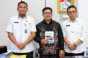 Sekda, Hermansyah berfoto bersama finalis IRIFair 2026, M. Arif Rahman Hakim (tengah) yang memegang modul riset "Arakan Sahur", dan Kepala Bapperida Tanjab Barat, Dr. H. Feri Elvianto, (kanan), usai audiensi dukungan riset robotika tingkat nasional di ruang kerja Sekda, Rabu (16/09). (Dok. Prokopim Tanjab Barat)