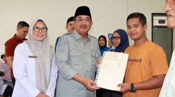 PENYERAHAN SERTIFIKAT: Bupati Tanjung Jabung Barat, Anwar Sadat, menyerahkan secara simbolis sertifikat tanah hasil konsolidasi kepada salah satu warga Kelurahan Teluk Nilau di Aula Kantor Camat Pengabuan, Rabu (08/04). Program ini mencakup 41 hektare lahan untuk memperkuat legalitas aset masyarakat. (FOTO : Dok. Prokopim)