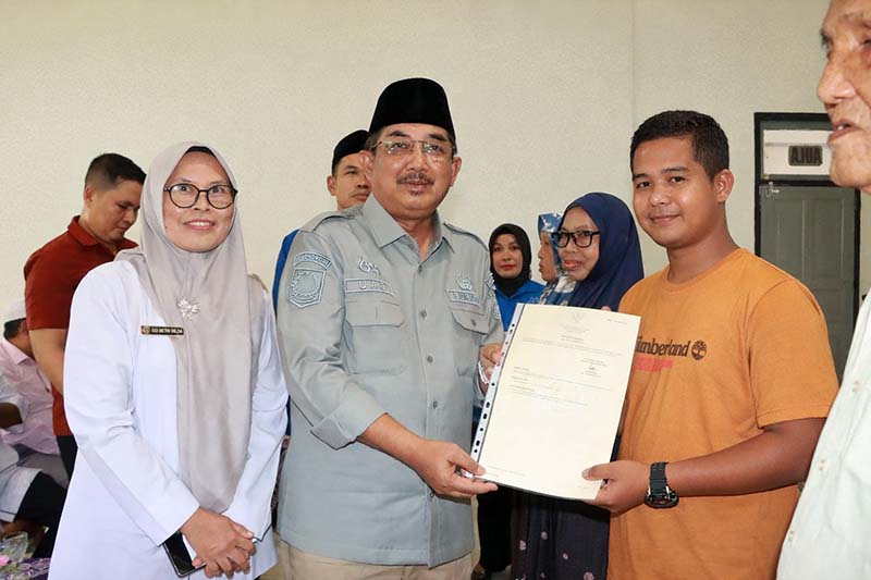 PENYERAHAN SERTIFIKAT: Bupati Tanjung Jabung Barat, Anwar Sadat, menyerahkan secara simbolis sertifikat tanah hasil konsolidasi kepada salah satu warga Kelurahan Teluk Nilau di Aula Kantor Camat Pengabuan, Rabu (08/04). Program ini mencakup 41 hektare lahan untuk memperkuat legalitas aset masyarakat. (FOTO : Dok. Prokopim)