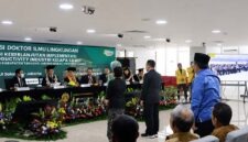Bupati H. Anwar Sadat, (berdiri mengenakan kemeja batik biru dan peci hitam), menghadiri Sidang Terbuka Promosi Doktor Estiarty Haryani, S.Pt., M.T., di Kampus Universitas Indonesia, Salemba, Jakarta Pusat, Sabtu (4/7). Dalam sidang tersebut, Estiarty mempertahankan disertasinya yang meneliti strategi produktivitas hijau (green productivity) industri kelapa sawit dengan lokus penelitian di Kabupaten Tanjung Jabung Barat, Jambi. (Foto: Dok. Prokopim Tanjabbar)