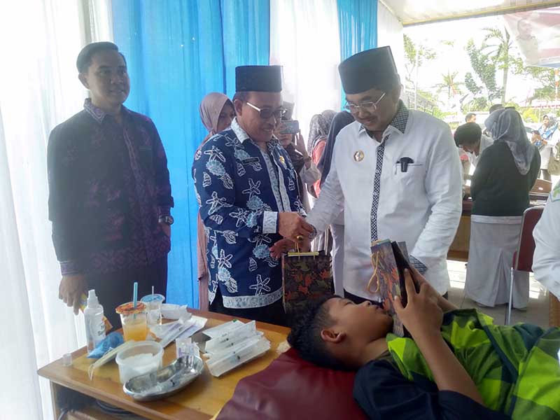 Bupati Tanjung Jabung Barat H Anwar Sadat didampingi Kepala Dinas Kesehatan H Zaharuddin bagikan bingkisan kepada Anak yang di Khitan, Rabu (2/8/23). FOTO : LT