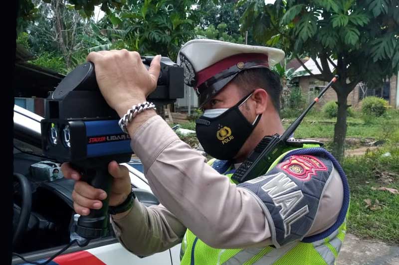Anggota Satuan Lalu Lintas Polres Muaro Jambi Menggunakan Speed Gan Mengukur Kecepatan dan Kelambatan Kendaraan di Jalan Raya, Kamis (10/3/22). FOTO : HUMAS PMJ