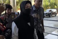 Bupati Sukoharjo Etik Suryani (tengah) berjalan dengan pengawalan usai menjalani pemeriksaan awal di Polresta Surakarta, Jawa Tengah, Jumat (10/7/2026). (FOTO : Dok. Istimewa/Kompas.com