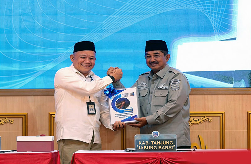 Bupati Tanjung Jabung Barat, Drs. H. Anwar Sadat, M.Ag (kanan), menyerahkan Laporan Keuangan Pemerintah Daerah (LKPD) Unaudited Tahun Anggaran 2025 kepada Kepala BPK Perwakilan Provinsi Jambi, Muhamad Toha, SE., M.Si (kiri), di Auditorium BPK Jambi, Selasa (31/03). (FOTO : Dok. Prokopim)