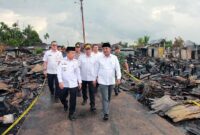 Gubernur Jambi Al Haris didampingi Bupati Tanjab Barat Anwar Sadat dan rombongan berjalan di antara puing-puing sisa kebakaran saat meninjau langsung lokasi terdampak di Kelurahan Teluk Nilau, Rabu (6/5/2026). Kunjungan ini bertujuan untuk menyerahkan bantuan sekaligus memastikan percepatan pemulihan bagi 70 kepala keluarga yang kehilangan tempat tinggal. (FOTO : Dok. PROKOPIM)