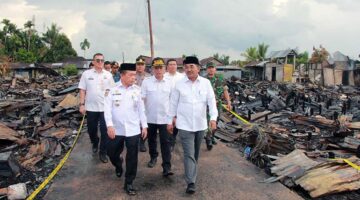 Gubernur Jambi Al Haris didampingi Bupati Tanjab Barat Anwar Sadat dan rombongan berjalan di antara puing-puing sisa kebakaran saat meninjau langsung lokasi terdampak di Kelurahan Teluk Nilau, Rabu (6/5/2026). Kunjungan ini bertujuan untuk menyerahkan bantuan sekaligus memastikan percepatan pemulihan bagi 70 kepala keluarga yang kehilangan tempat tinggal. (FOTO : Dok. PROKOPIM)