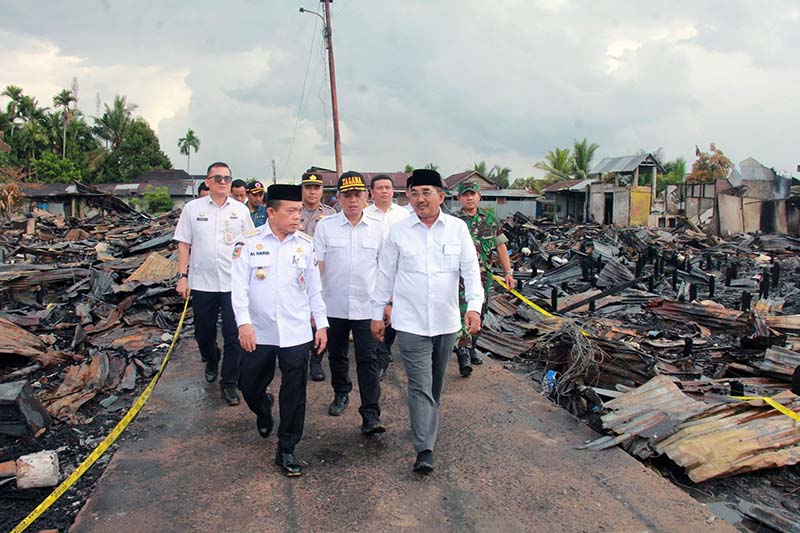 Gubernur Jambi Al Haris didampingi Bupati Tanjab Barat Anwar Sadat dan rombongan berjalan di antara puing-puing sisa kebakaran saat meninjau langsung lokasi terdampak di Kelurahan Teluk Nilau, Rabu (6/5/2026). Kunjungan ini bertujuan untuk menyerahkan bantuan sekaligus memastikan percepatan pemulihan bagi 70 kepala keluarga yang kehilangan tempat tinggal. (FOTO : Dok. PROKOPIM)