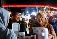 Bupati H. Anwar Sadat dan Ketua TP PKK Hj. Fadhilah Sadat saat berinteraksi langsung dengan pedagang di Bazar UMKM Alun-Alun Kota Kuala Tungkal, Selasa (5/8). Bupati dan istri juga memborong produk lokal untuk dibagikan gratis kepada warga sekitar sebagai bentuk dukungan nyata bagi ekonomi rakyat. (FOTO : Dok. Prokopim)