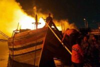 Petugas berusaha memadamkan api di Pelabuhan Perikanan Pantai (PPP) Tegalsari atau lebih dikenal Pelabuhan Jongor Tegal, Senin (14/8/23). FOTO : tribunbanyumas